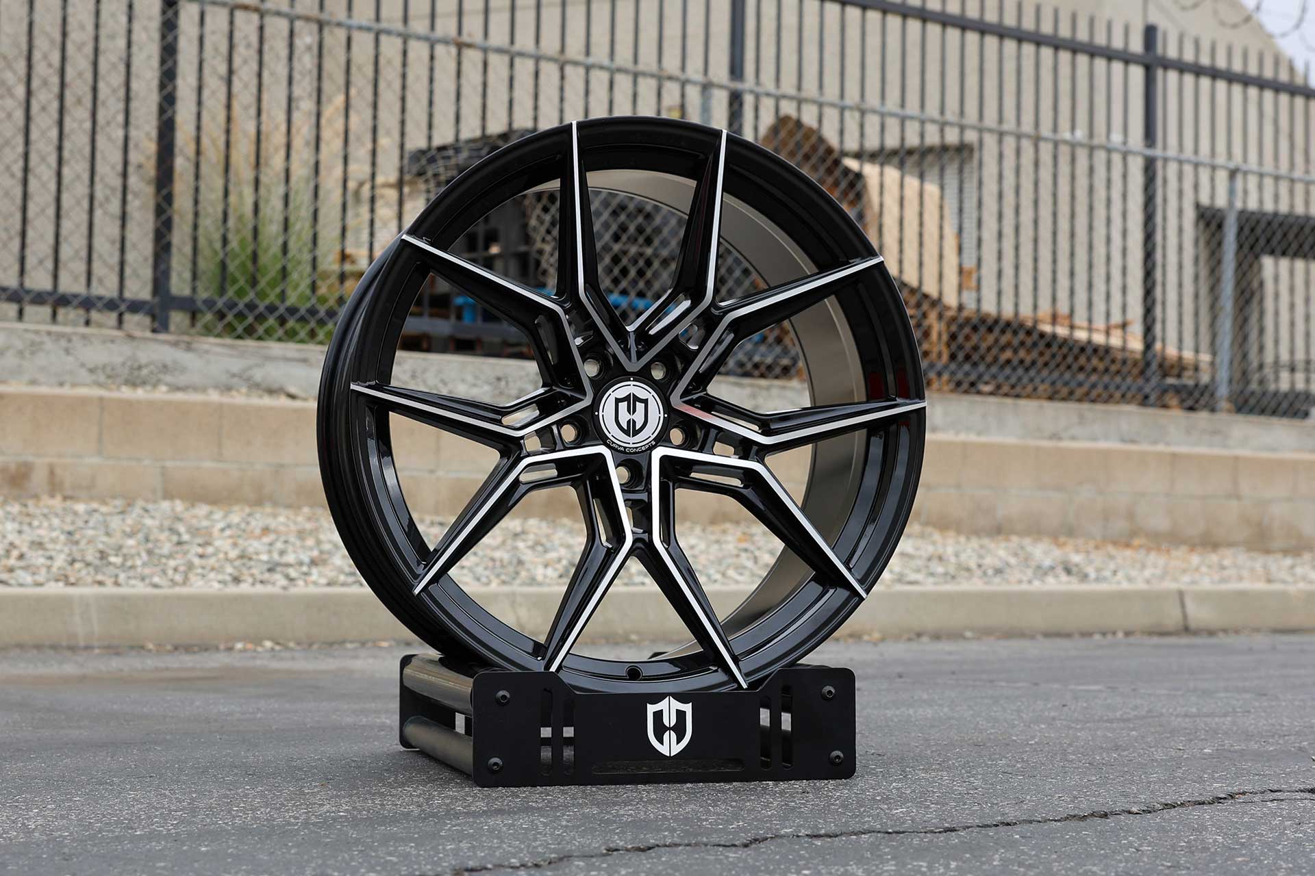 curva concepts cff43 gloss black machined performance wheel with polished accents on branded display stand outdoors